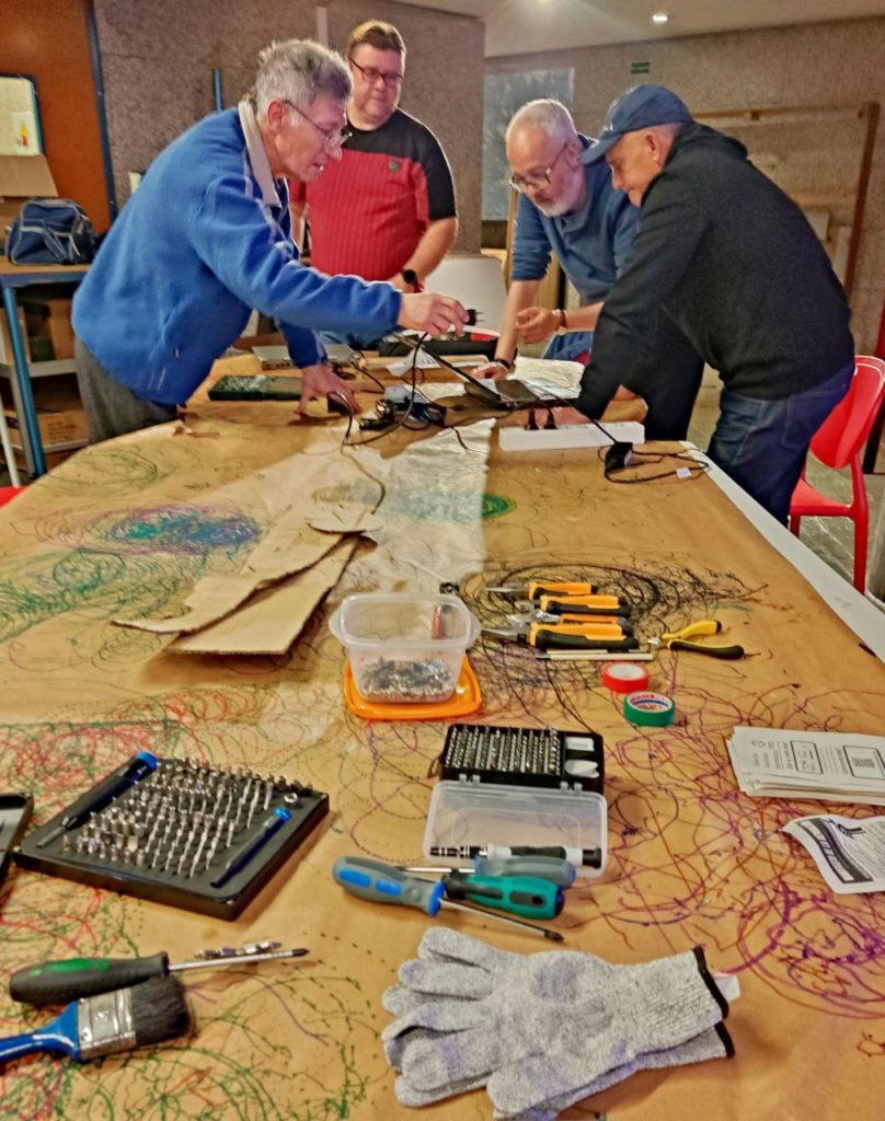 Imaxes do I Repair Café na Domus - 26 de abril
Varias persoas distribuidas en 4 mesas arranxando varios aparatos electrónicos